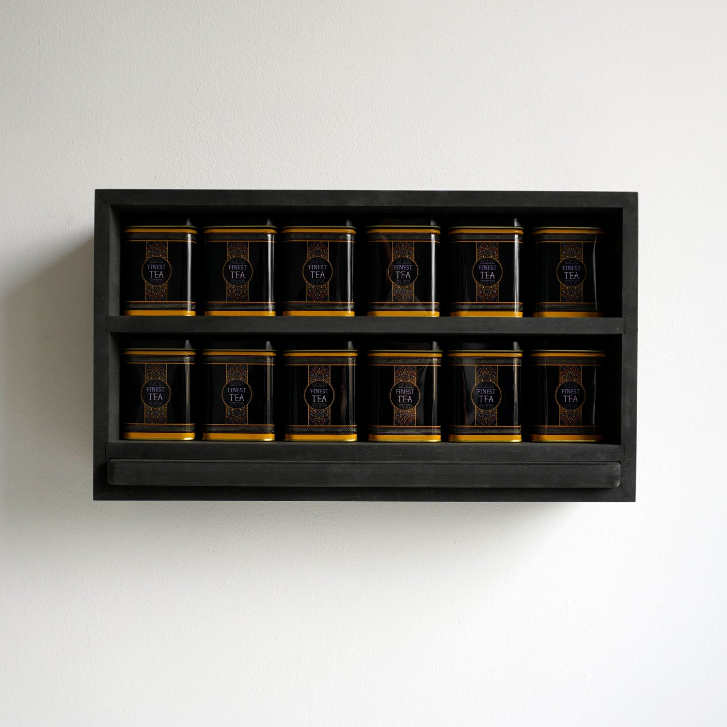 Vooraanzicht van een theerek met finest tea blikken en zwarte serveerplank