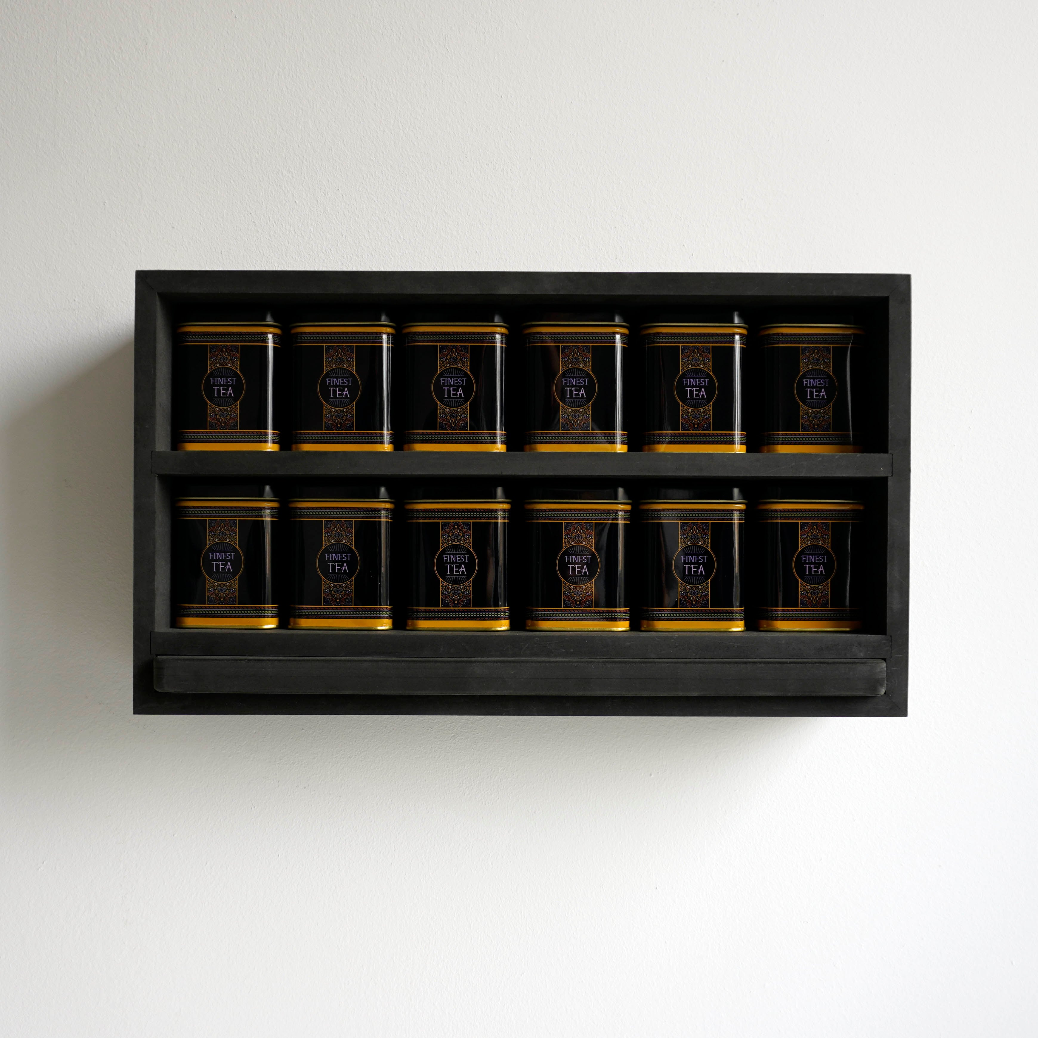 Vooraanzicht van een theerek met finest tea blikken en zwarte serveerplank