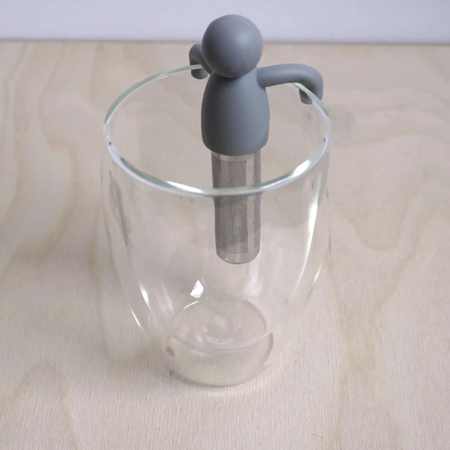 Vooraanzicht van een theefilter met een hangend mannetje in een glas