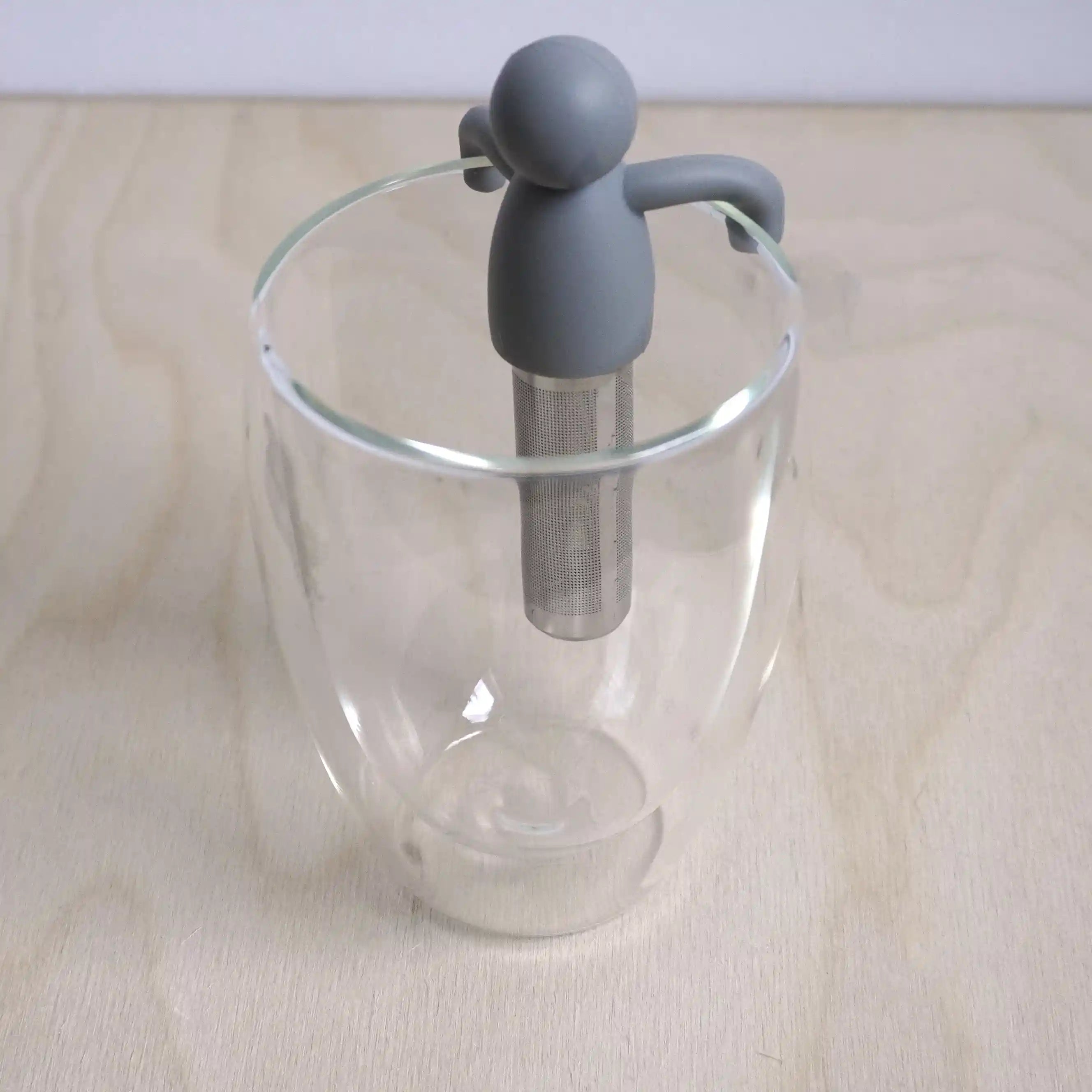 Vooraanzicht van een theefilter met een hangend mannetje in een glas