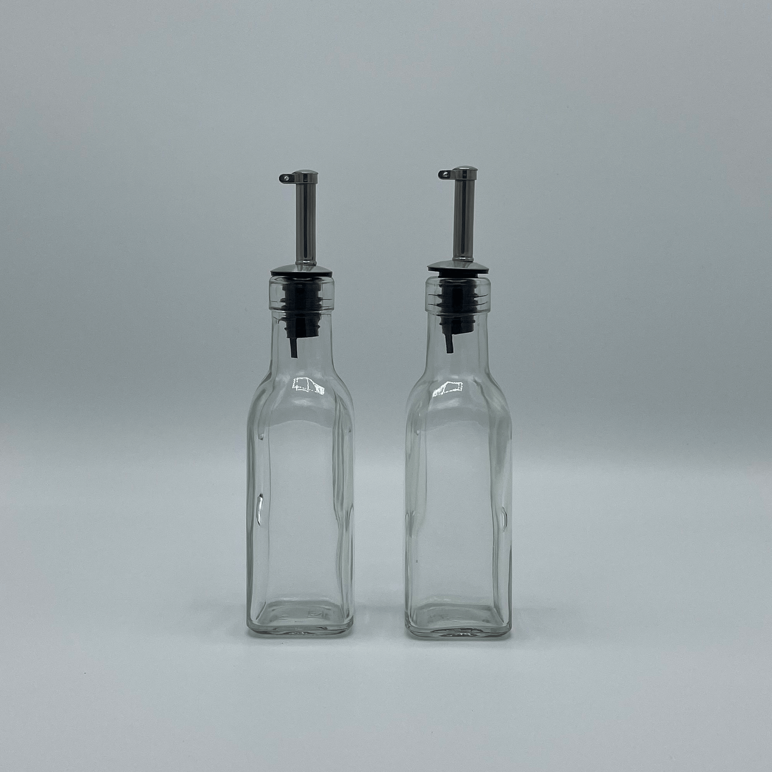 Twee lege olieflesjes met schenkdop