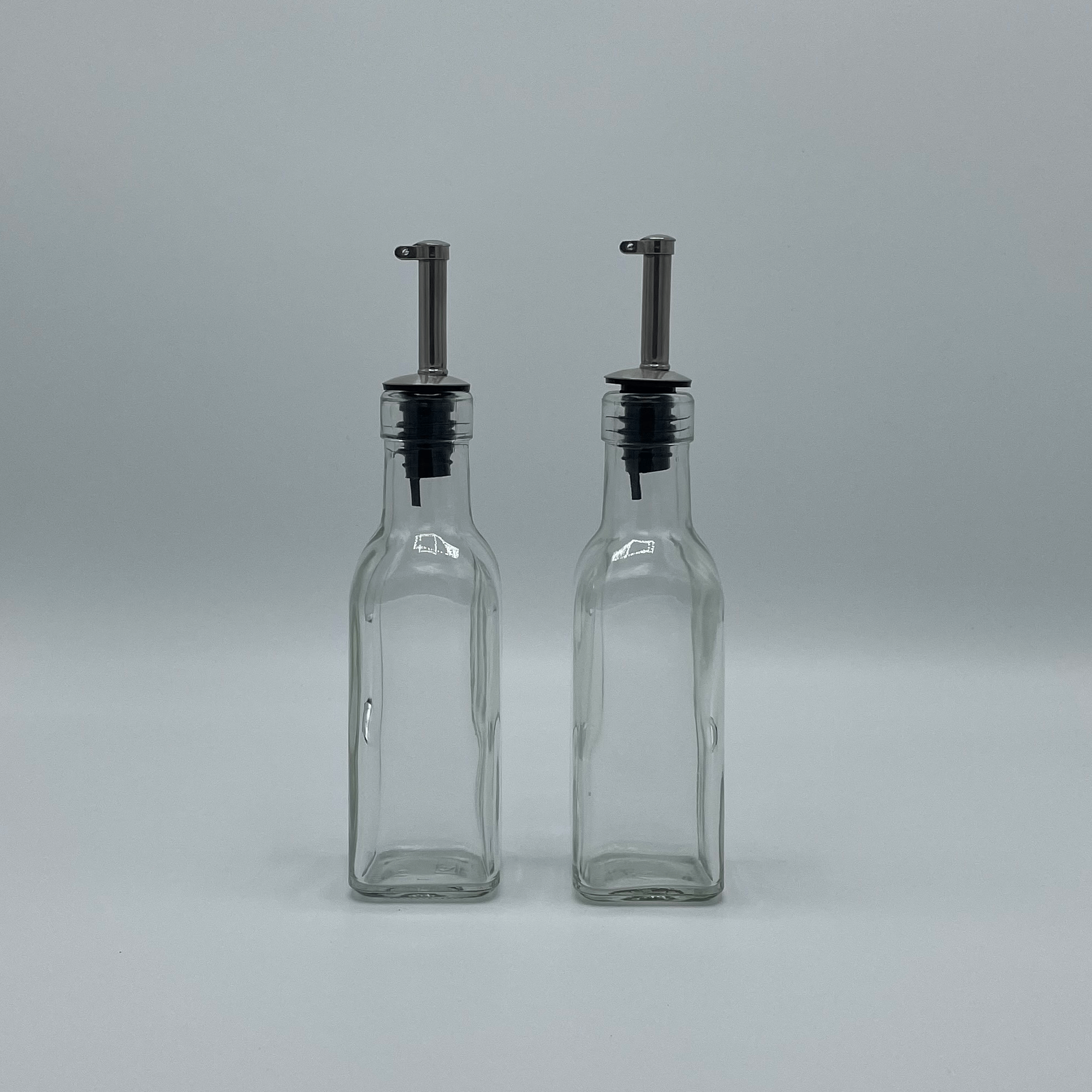 Twee lege olieflesjes met schenkdop