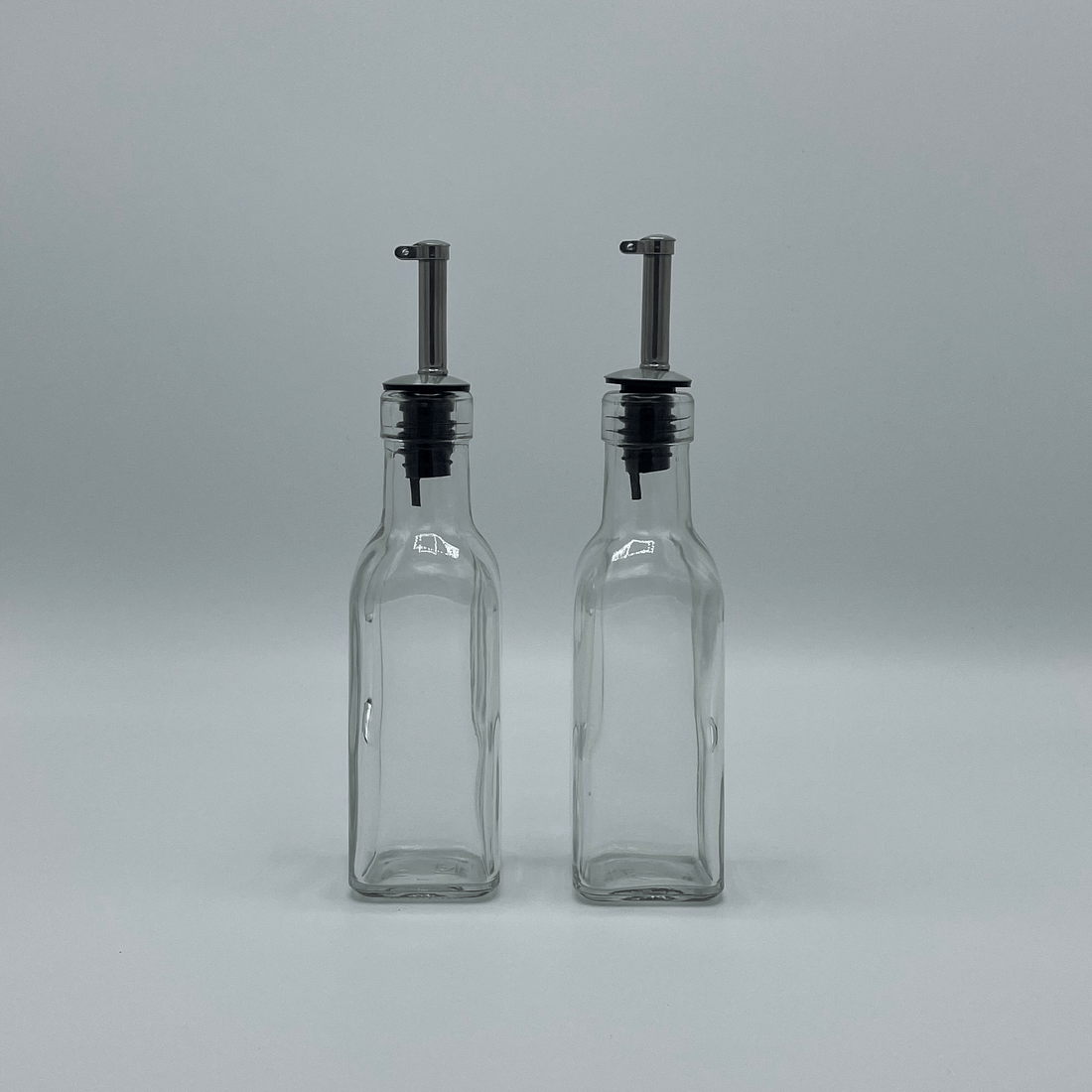 Twee lege olieflesjes met schenkdop